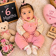 Taqdeer is registered to the contest to win money with this photo: baby, infant, six_months, child, portrait, smiling, sitting, pink, overalls, floral_clothing, hair_bow, teddy_bear, flowers, bouquet, chalkboard, wooden_blocks, blanket, nursery, birthday_theme, studio_photography