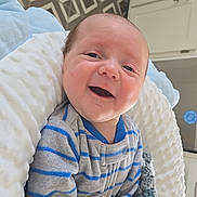 Wilder joined the competition — help win amazing prizes! baby, infant, newborn, smile, happy, onesie, striped_clothing, blanket, knitted_blanket, cushion, face, head, hand, fingers, mouth_open, indoor, kitchen_cabinets, patterned_floor, portrait, cozy