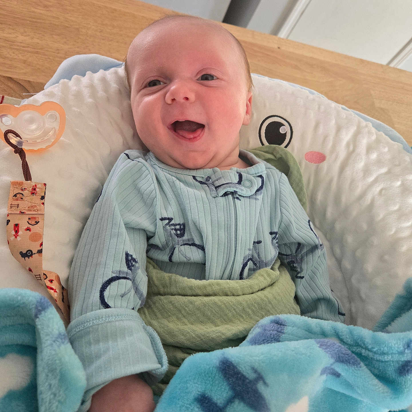 Wilder joined the competition — help win amazing prizes! baby, blanket, bouncer, clothing, cozy, cushion, face, hand, happy, indoor, infant, newborn, nursery, onesie, pacifier, pacifier_clip, portrait, smile, soft_toy, wooden_table