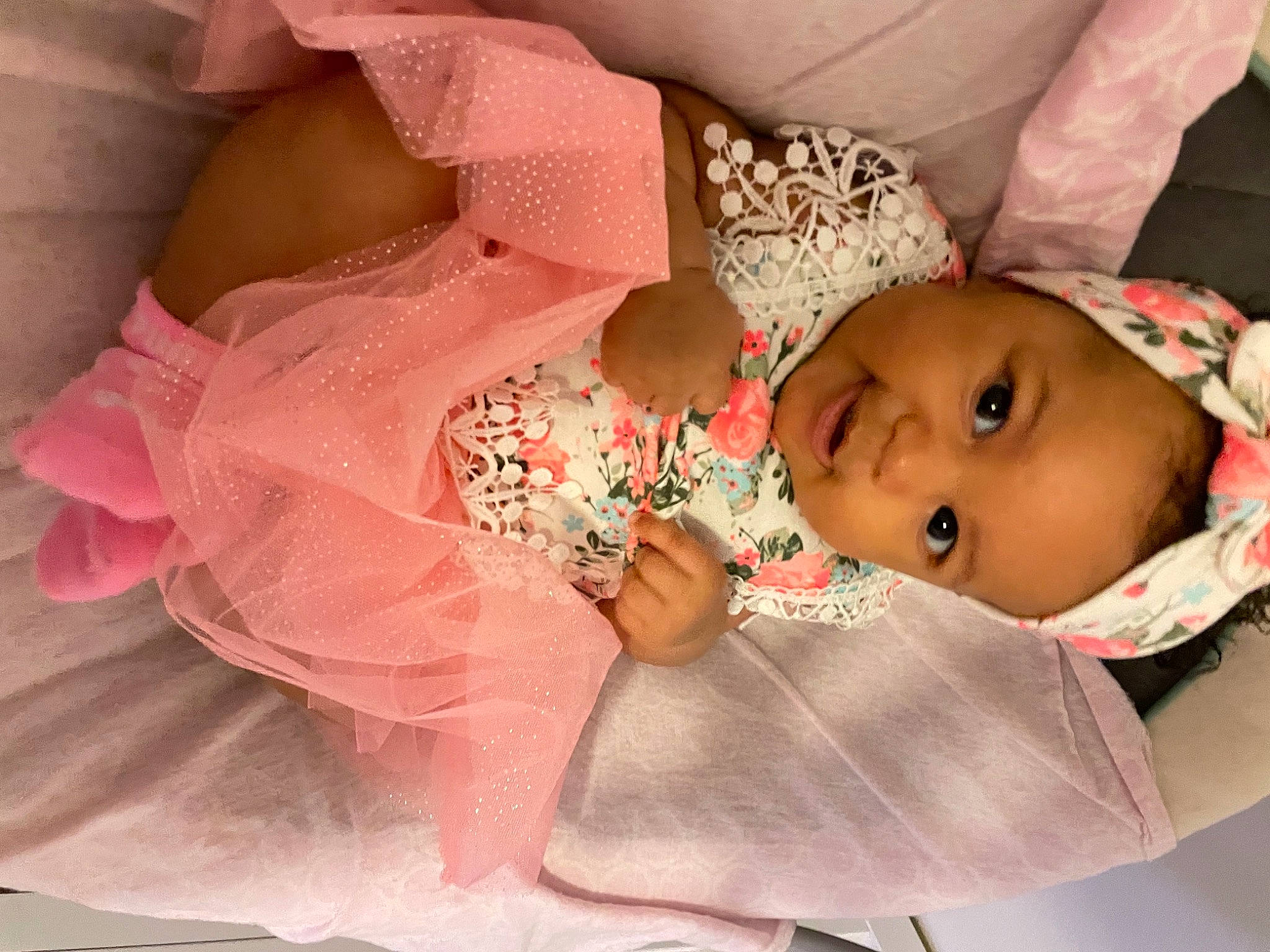 Lovee is registered to the contest to win money with this photo: baby, baby_products, baby_toddler_clothing, cheek, dress, embellishment, eyelash, fashion_accessory, hair_accessory, happy, head, headgear, iris, linens, lip, peach, person, pink, skin, sleeve