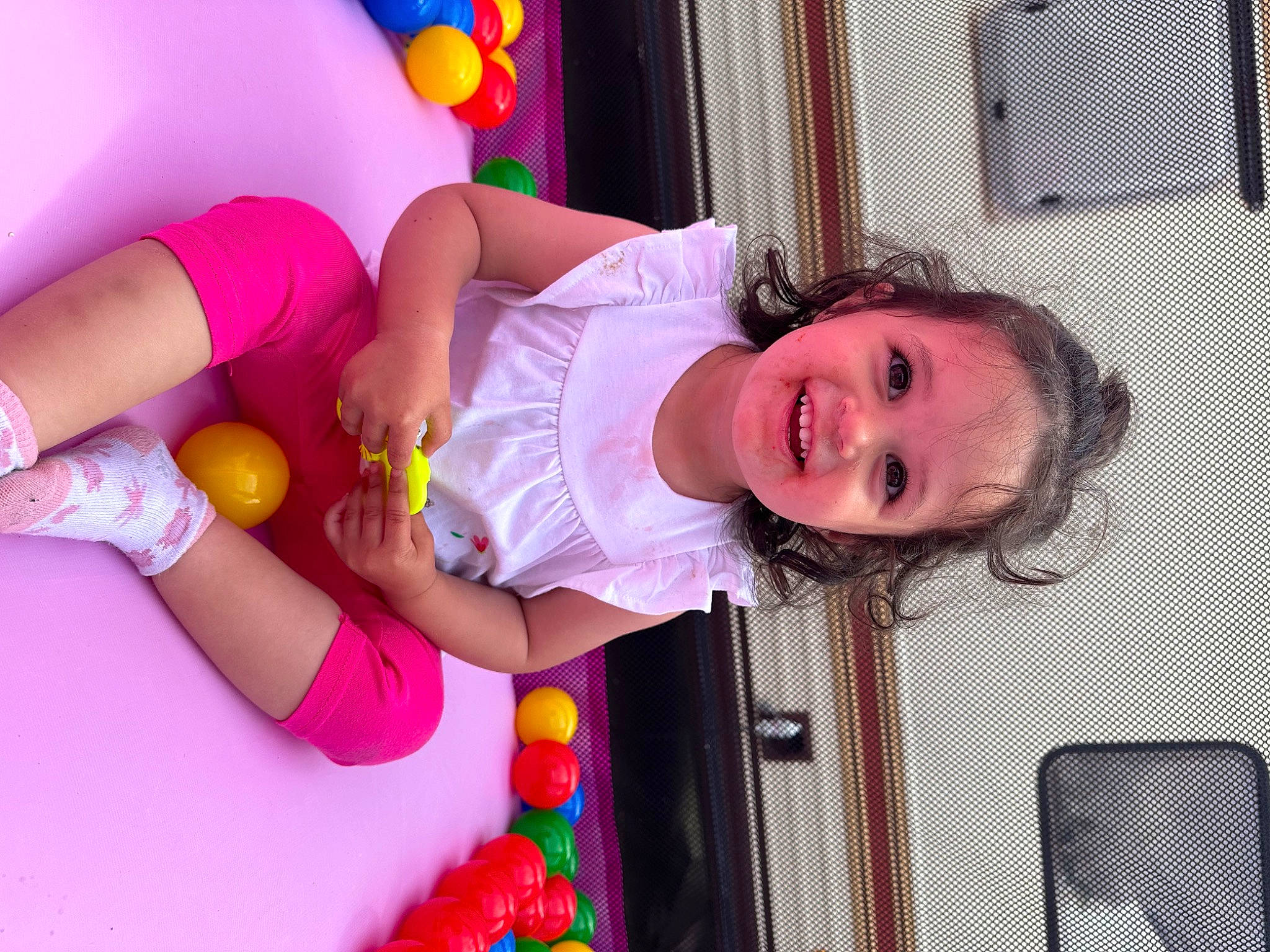 Mia participe au concours pour gagner de l'argent avec cette photo : baby_playing_with_toys, baby_toddler_clothing, child, eye, facial_expression, fun, happy, human_leg, joy, leg, leisure, magenta, party_supply, person, pink, shorts, smile, textile, thigh, toddler