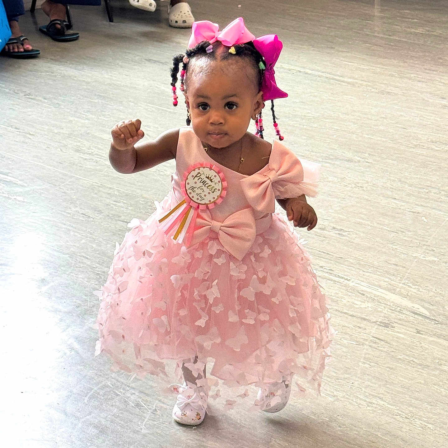 Elsie is registered to the contest to win money with this photo: badge, beads, bows, braided_hair, celebration, child, confident, cute, fashion, floor, flooring, girl, indoor, party, people, pink_dress, ribbon, shoes, walking, young_child