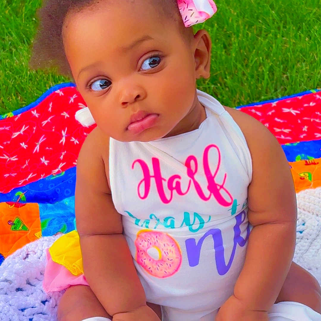 Elorah joined the competition — help win amazing prizes! baby, bow, child, clothing, colorful, cute, expression, face, grass, infant, leg_warmers, nature, outdoor, pink, portrait, quilt, sitting, summer, toddler, white