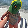 baby, child, cap, john_deere, onesie, bare_bottom, hand, water, beach_chair, striped, sunlight, shadow, outdoor, person, infant, summer, nature, shore, concrete, cute