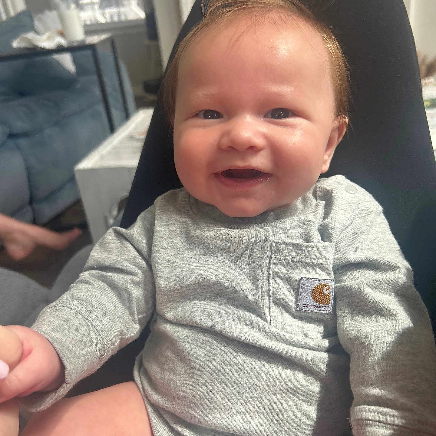 Hardin is registered to the contest to win money with this photo: baby, child, couch, cute, face, furniture, grey_clothing, hand, happy, indoor, infant, living_room, natural_light, onesie, person, sitting, skin, smiling, table, window