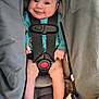 baby, infant, car_seat, smile, child, headband, clothing, safety_harness, cute, happy, person, seat, blanket, small_child, legs, portrait, indoors, comfort, baby_toys, pacifier