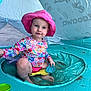 toddler, child, pink_hat, floral_shirt, swimwear, inflatable_pool, beach_tent, sand_toys, sitting, play, outdoor, summer, water, beach, toy_shovel, toy_sand_mold, cute, sun_protection, fun, smiling