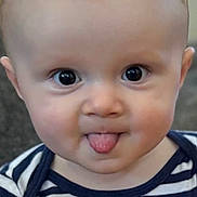 Roland is registered to the contest to win money with this photo: baby, child, tongue_out, striped_shirt, fire_truck_patch, cute, portrait, face, big_eyes, infant, cheeky, close_up, smiling, adorable, young_child, indoor, person, head, expression, clothing