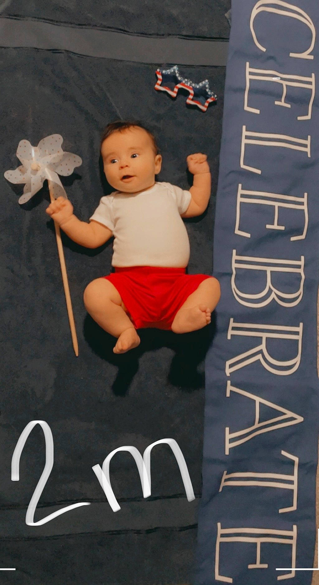 Logan is registered to the contest to win money with this photo: baby, baby_products, baby_toddler_clothing, baby_toys, carmine, carpet, chair, child, design, flooring, font, happy, linens, person, product, room, sitting, sleeve, t_shirt, toddler