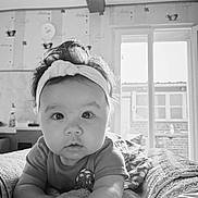 Marion a rejoint le concours — aidez-le/la à gagner de superbes lots ! baby, headband, bed, blanket, indoor, infant, face, curious, wide_eyes, portrait, monochrome, soft_lighting, clothing, hand, wallpaper, window, room, cozy, child, person