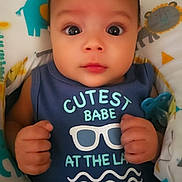 Elyzah is registered to the contest to win money with this photo: baby, infant, child, blue_onesie, text_on_clothing, animal_print, blanket, cute, portrait, indoors, pacifier, hands, face, wide_eyes, looking_at_camera, soft_lighting, adorable, young_child, comfortable, baby_bedding