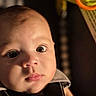 baby, face, child, portrait, closeup, expression, curious, infant, skin, eyes, cheeks, lighting, indoors, clothing, baby_seat, soft_light, young, cute, head, person