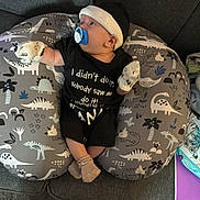 Lucas joined the competition — help win amazing prizes! baby, infant, pacifier, beanie, mittens, socks, nursing_pillow, dinosaur_pattern, patterned_pillow, couch, sofa, onesie, black_onesie, carpet, living_room, blanket, tissue, adult_socks, home_interior, candid_photo