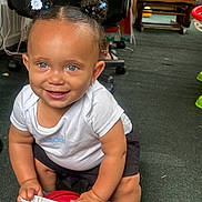 Jusara is registered to the contest to win money with this photo: baby, basketball, black_shorts, blue_eyes, carpet, chair, child, cute, floor, hair_buns, happy, indoor, person, playful, small_basketball, smiling, sneakers, toddler, toy, white_shirt