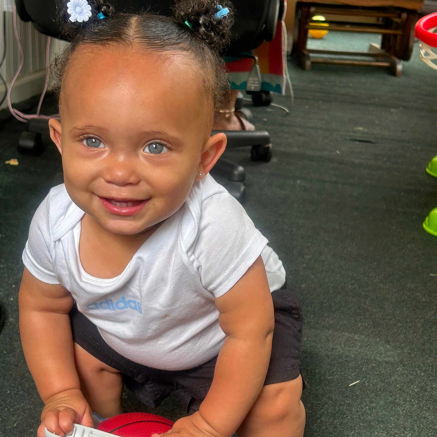 Jusara is registered to the contest to win money with this photo: baby, basketball, black_shorts, blue_eyes, carpet, chair, child, cute, floor, hair_buns, happy, indoor, person, playful, small_basketball, smiling, sneakers, toddler, toy, white_shirt