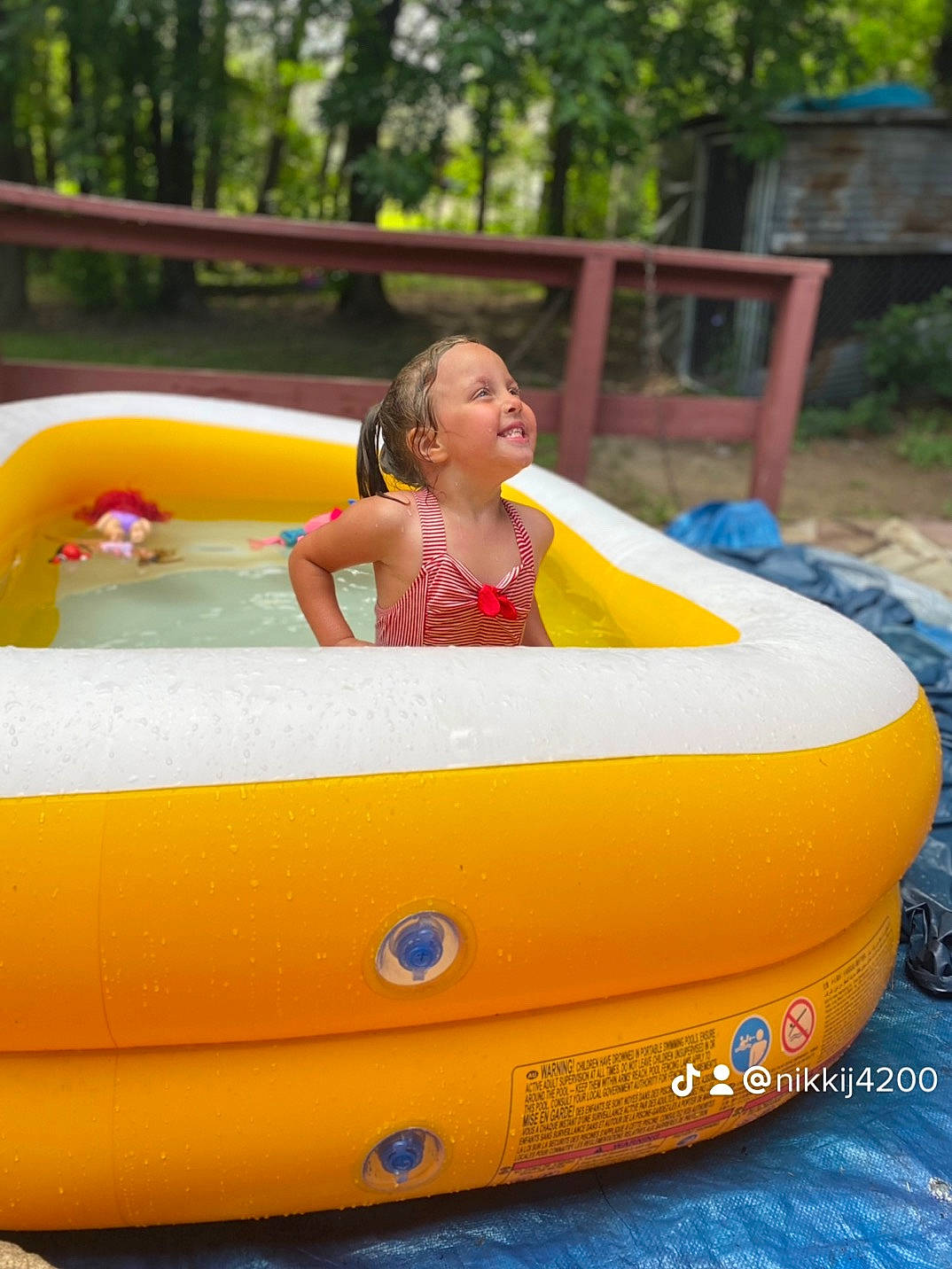 Hazel is registered to the contest to win money with this photo: automotive_exterior, bathing, bumper, child, fun, happy, inflatable, joy, leisure, motor_vehicle, nonbuilding_structure, person, plant, play, recreation, smile, summer, toddler, tree, vacation