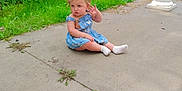 Sydney is registered to the contest to win money with this photo: toddler, child, blue_dress, white_socks, sitting, porch, concrete, greenery, plants, pillars, outdoor, daylight, curious, cute, casual, nature, grass, small_child, person, young_kid