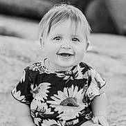 Sydney is registered to the contest to win money with this photo: child, toddler, smiling, portrait, black_and_white, flower_pattern, sunflower, happy, cute, face, short_hair, baby, clothing, person, infant, outdoor, sitting, young_child, joyful, closeup