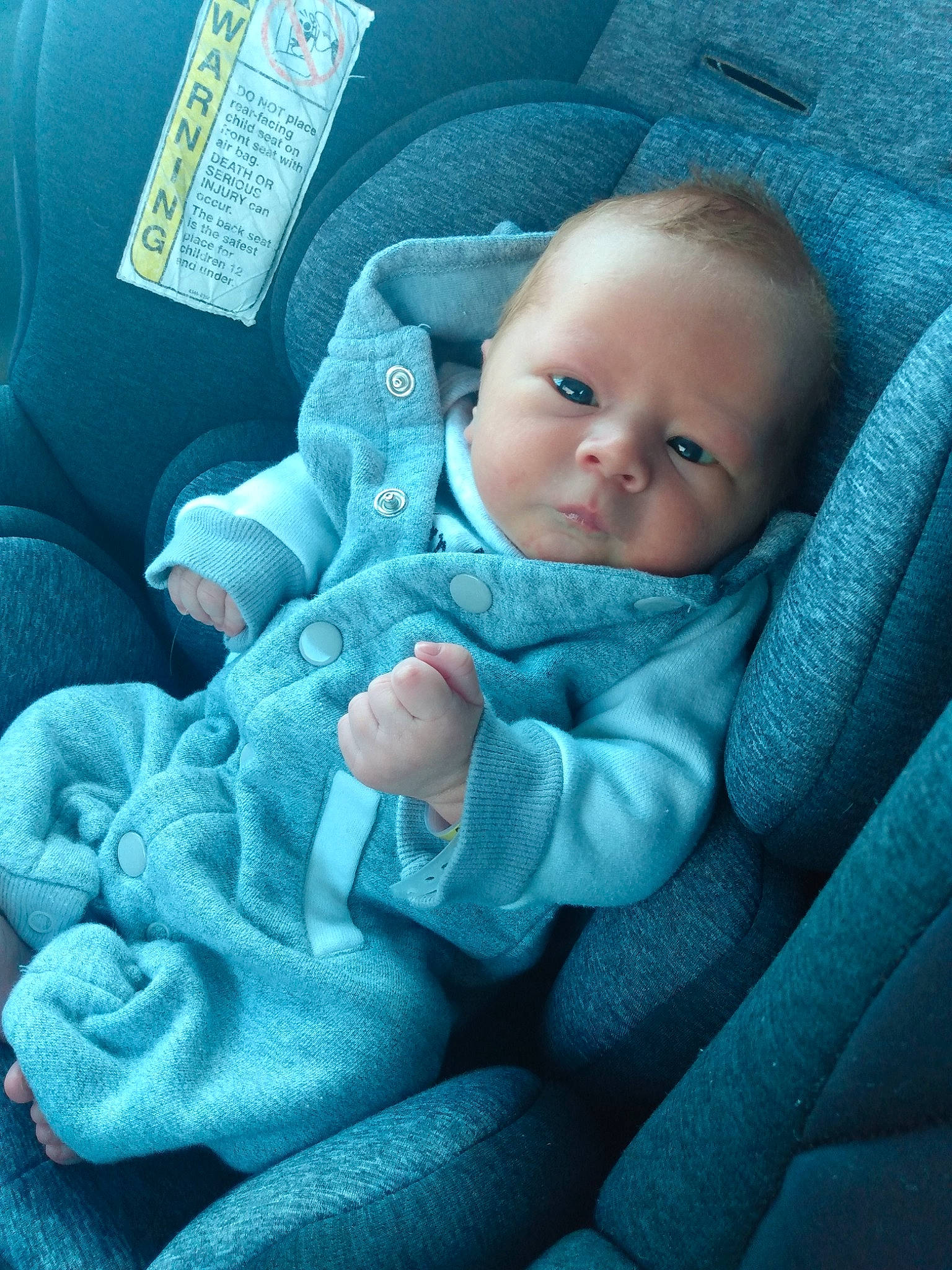 Shane is registered to the contest to win money with this photo: auto_part, azure, baby, baby_products, baby_toddler_clothing, blue, car_seat, cheek, child, comfort, electric_blue, finger, grey, linens, person, product, sitting, skin, textile, thumb