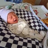 newborn, baby, infant, hat, onesie, checkered_cushion, food_box, fries, sauce, bedroom, quilt, blanket, sleeping, yawning, cozy, indoor, cute, person, resting, soft_lighting