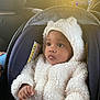 baby, car, car_seat, child, coat, cozy, cute, fluffy, hood, indoors, infant, looking_away, portrait, seatbelt, sunlight, vehicle_interior, warm, warm_clothing, white, young_child