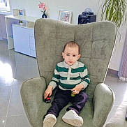 Lyam participe au concours pour gagner de l'argent avec cette photo : child, boy, rocking_chair, toy_cars, striped_shirt, living_room, mirror, plant, floor_tiles, modern_furniture, decor, indoor, casual_clothing, white_shoes, cabinet, photograph_frame, vase, window, curtains, happy