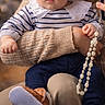 baby, child, adult, smile, face, headband, striped_shirt, knit_sweater, pearl_necklace, blue_pants, brown_boots, holding, person, portrait, indoor, warm_lighting, cute, expression, cozy, family