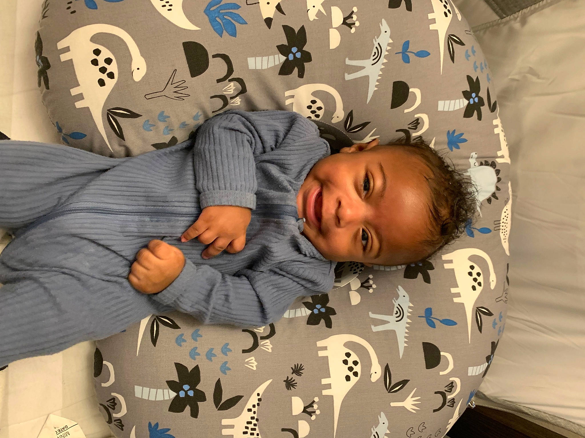 Romell is registered to the contest to win money with this photo: arm, baby, baby_toddler_clothing, child, comfort, eye, gesture, hairstyle, happy, head, linens, pattern, people, person, product, room, sleeve, smile, textile, toddler