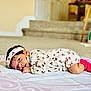 baby, infant, lying_down, blanket, headband, floral_outfit, pink_socks, indoors, carpet, face, person, cute, child, young_child, home, soft_lighting, portrait, looking, resting, cozy
