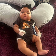 A'Jshanae joined the competition — help win amazing prizes! baby, black_onesie, child, chubby_legs, comfort, cozy, cushion, cute, headband, indoors, infant, lying_down, maroon_surface, mittens, pillow, relaxation, rest, small_person, soft_fabric, teddy_bear_print