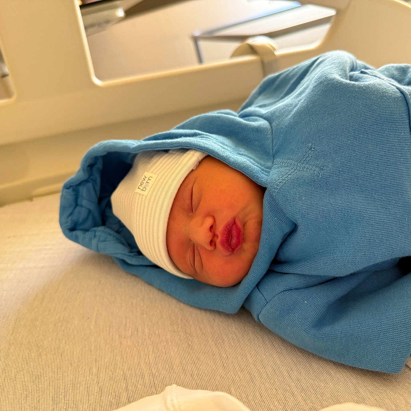 Milano participe au concours pour gagner de l'argent avec cette photo : baby, blue_hoodie, child, closeup, cozy, cute, face, hospital_bed, indoors, infant, newborn, peaceful, person, portrait, puckered_lips, resting, sleeping, soft_fabric, white_hat, wrapped