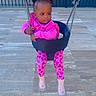 toddler, child, swing, playground, pink_clothing, chains, outdoor, fence, curious, sitting, shoes, patterned_leggings, hairstyle, daytime, tiles, person, young_child, play, fun, baby