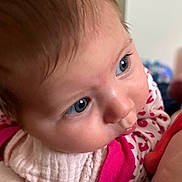 Aurora is registered to the contest to win money with this photo: baby, close_up, blue_eyes, infant, cute, pink_clothing, heart_pattern, soft_texture, face, skin, hair, resting, indoors, portrait, child, young, person, cozy, expression, curious