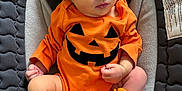 Aurora is registered to the contest to win money with this photo: newborn, baby, sleeping, orange_clothing, pumpkin_face, headband, flower, booties, infant, baby_seat, quilted_padding, soft_fabric, peaceful, cute, portrait, indoors, closeup, hands, legs, cozy