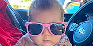 Aurora joined the competition — help win amazing prizes! baby, child, pink_sunglasses, car_interior, hand, clothing, floral_embroidery, steering_wheel, person, portrait, cute, infant, sitting, fashion, nail_art, window, sunlight, seatbelt, casual, expression