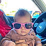 baby, car_interior, casual, child, clothing, cute, expression, fashion, floral_embroidery, hand, infant, nail_art, person, pink_sunglasses, portrait, seatbelt, sitting, steering_wheel, sunlight, window