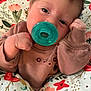 Aurora is registered to the contest to win money with this photo: baby, pacifier, floral_pattern, cushion, brown_clothing, hand, face, eyes, portrait, indoors, closeup, cute, infant, soft_lighting, expression, child, resting, comfort, skin, head