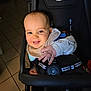 Mickaël participe au concours pour gagner de l'argent avec cette photo : baby, infant, smiling, stroller, car_seat, bib, hand, reaching, harness, buckle, face, eyes, cheek, tile_floor, indoor, clothing, cute, happy, portrait, seat