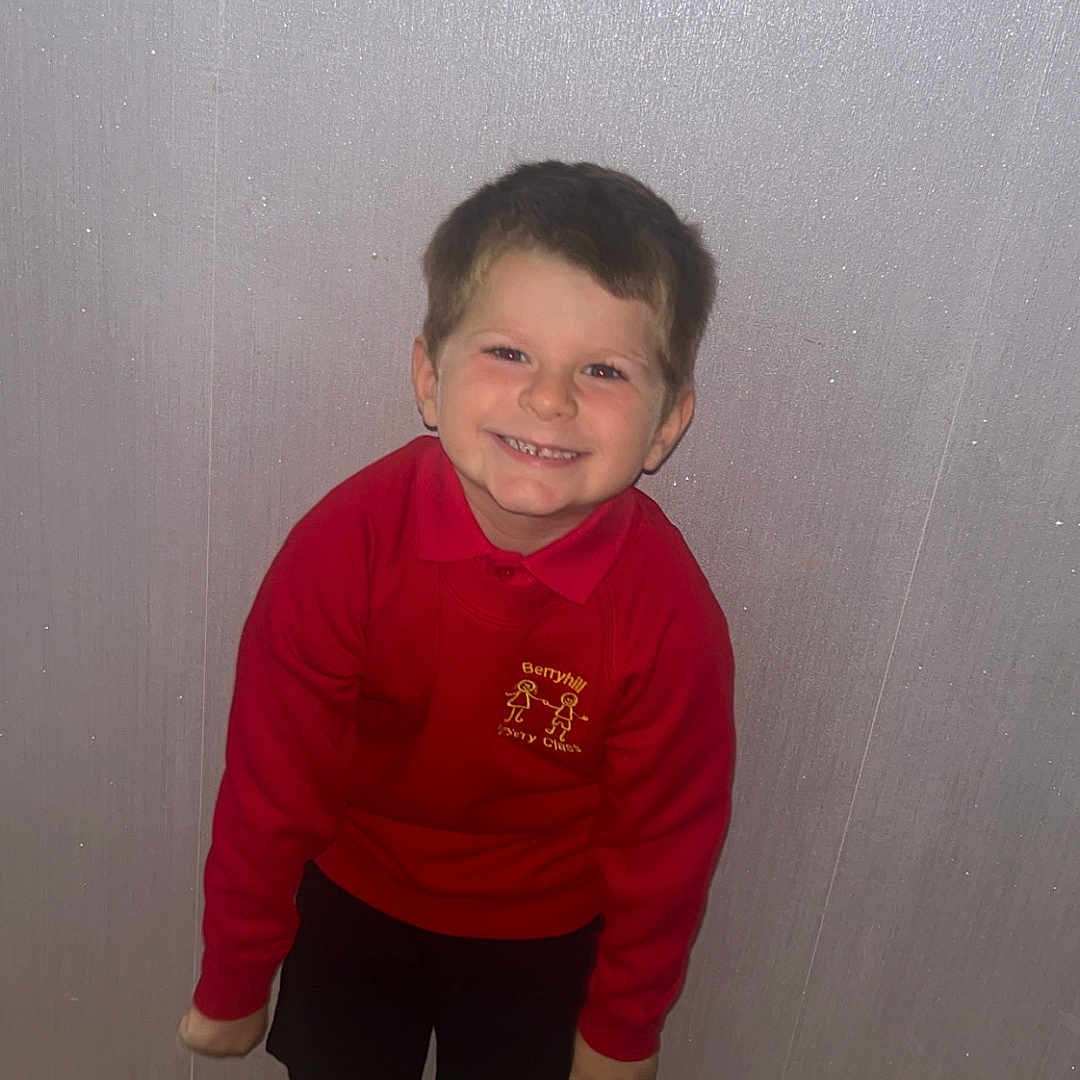 Claiton joined the competition — help win amazing prizes! boy, casual_clothing, child, cute, footwear, happy, home, indoor, person, playful, portrait, red_sweater, school_uniform, shorts, smiling, socks, spiderman, standing, wall, wooden_floor