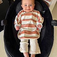 Alba a rejoint le concours — aidez-le/la à gagner de superbes lots ! baby, child, smile, face, bib, striped_clothing, pants, feet, cushion, seat, indoor, brick_wall, happy, person, infant, head, skin, footwear_free, comfort, casual