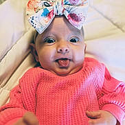 Iris Rain joined the competition — help win amazing prizes! baby, infant, bow, headwear, pink_sweater, tongue_out, closeup, cute, child, playful, expression, soft_blanket, indoors, portrait, small_hands, wide_eyes, colorful, texture, happy, adorable