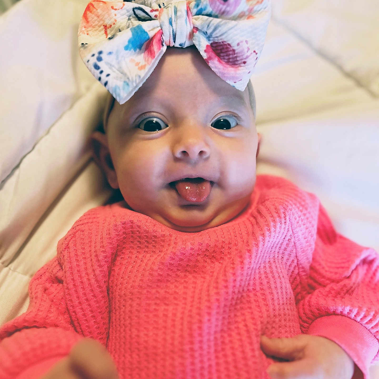 Iris Rain joined the competition — help win amazing prizes! baby, infant, bow, headwear, pink_sweater, tongue_out, closeup, cute, child, playful, expression, soft_blanket, indoors, portrait, small_hands, wide_eyes, colorful, texture, happy, adorable