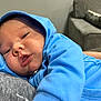 baby, blue_hoodie, close_up, indoor, couch, face, person, sleepy, child, infant, clothing, portrait, young_child, casual, relaxing, human, baby_clothes, comfort, resting, soft_lighting