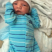 Luka is registered to the contest to win money with this photo: newborn, baby, infant, child, portrait, face, eyes_open, white_hat, blue_clothing, striped_outfit, onesie, mittens, blanket, bed, indoors, lying_down, cozy, hospital, close_up, photograph