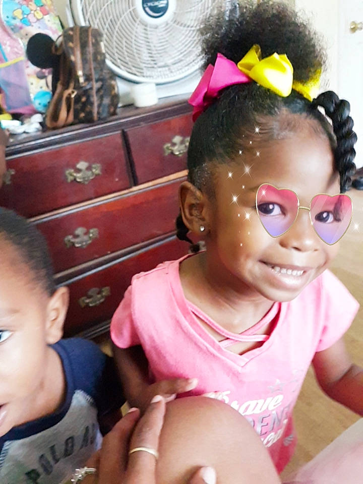 Jaleah is registered to the contest to win money with this photo: black_hair, cheek, child, cornrows, ear, eyelash, finger, forehead, hair, hair_accessory, hairstyle, head, joy, person, pink, smile, toddler