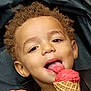 child, toddler, ice_cream, cone, red_ice_cream, double_scoop, curly_hair, happy, smiling, tongue_out, stroller, black_clothing, food, dessert, summer, sweet, snack, cute, person, closeup
