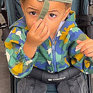 Darren a rejoint le concours — aidez-le/la à gagner de superbes lots ! child, boy, stroller, cap, backwards_cap, camouflage_jacket, cargo_pants, curious, brown_eyes, hand, outdoor, footwear, seated, young, person, clothing, fabric, seat, straps, casual