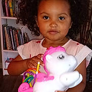 Myrtlelee joined the competition — help win amazing prizes! books, bookshelf, child, colorful, curly_hair, cute, dress, floor, home, indoor, person, pink, plant, playtime, smile, toddler, toy, unicorn, wooden_floor, young