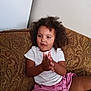 casual_clothing, child, clapping, comfortable, couch, curly_hair, cute, expression, face, home, indoor, legs, patterned_fabric, person, pink_shorts, sitting, skin, toddler, white_shirt, young
