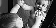 Riley is registered to the contest to win money with this photo: baby, child, mirror, reflection, diaper, hands, curious, black_and_white, indoor, carpet, expression, portrait, face, looking, standing, room, young, infant, cute, playful